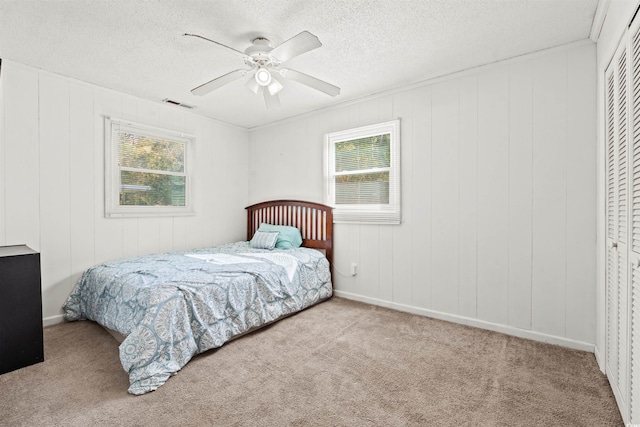 bedroom featuring multiple windows, carpet flooring, a textured ceiling, a closet, and ceiling fan