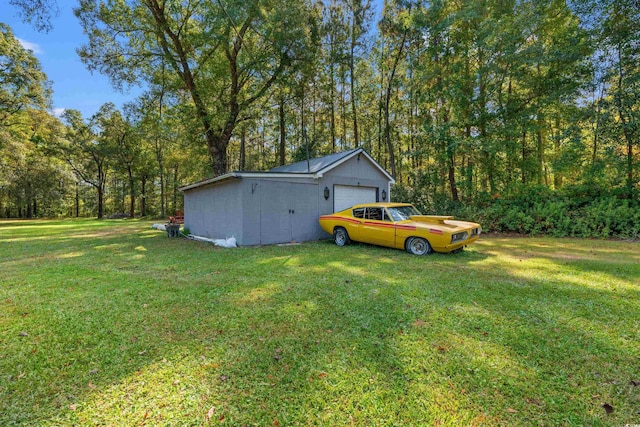 view of green lawn featuring an outbuilding, a view of trees, and a detached garage