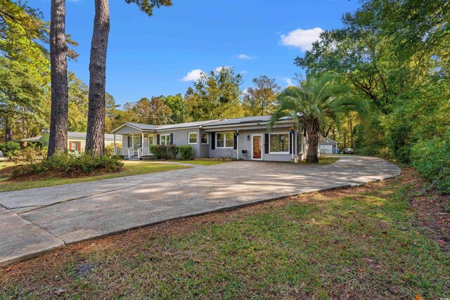 ranch-style house featuring concrete driveway, a porch, a front yard, and an attached garage