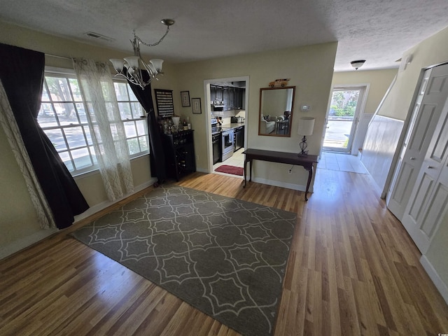 foyer with baseboards, a notable chandelier, wood finished floors, and visible vents