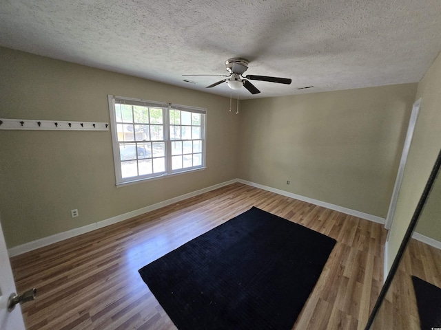 spare room featuring baseboards, a textured ceiling, ceiling fan, and wood finished floors
