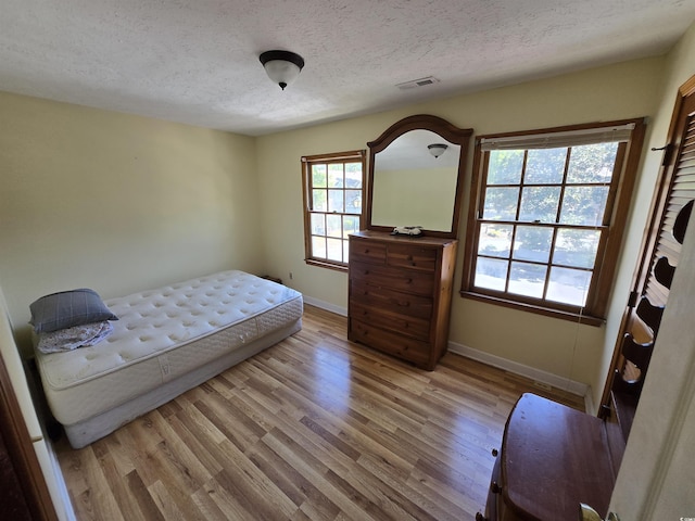 bedroom with a textured ceiling, multiple windows, and baseboards