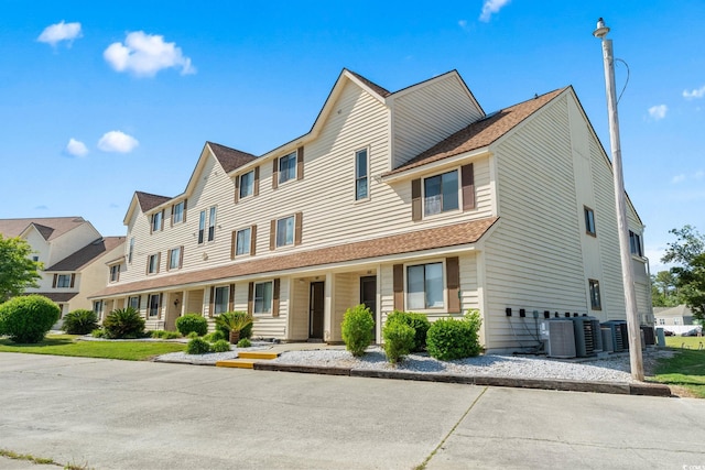 multi unit property featuring central air condition unit, a residential view, and a shingled roof