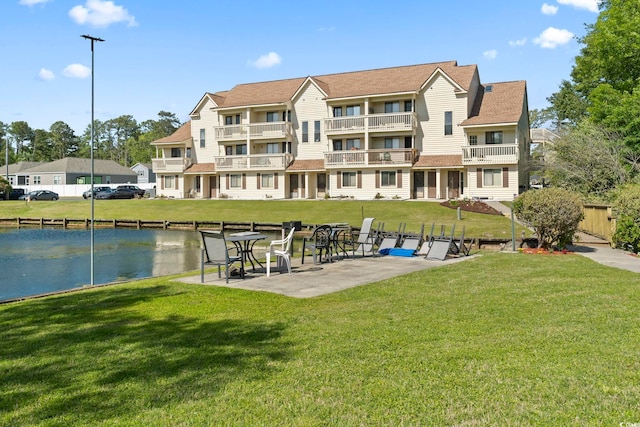 view of community featuring a water view, a yard, and a patio