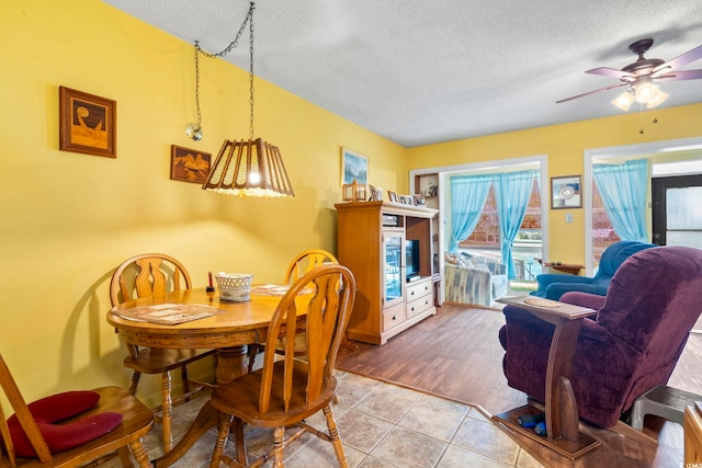 dining space with a textured ceiling, tile patterned floors, and ceiling fan