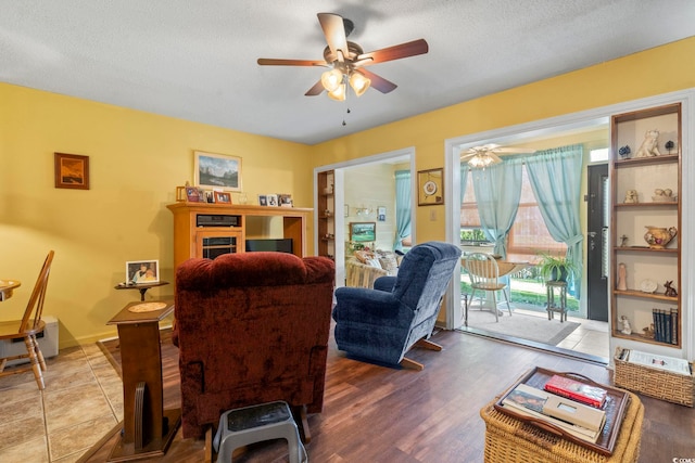 living room with ceiling fan, wood finished floors, and a textured ceiling