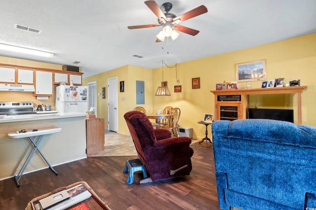 living area with wood finished floors, a ceiling fan, and electric panel