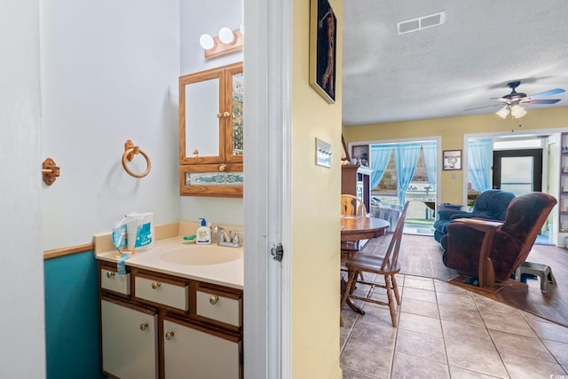 bathroom featuring ceiling fan, tile patterned flooring, a textured ceiling, and vanity