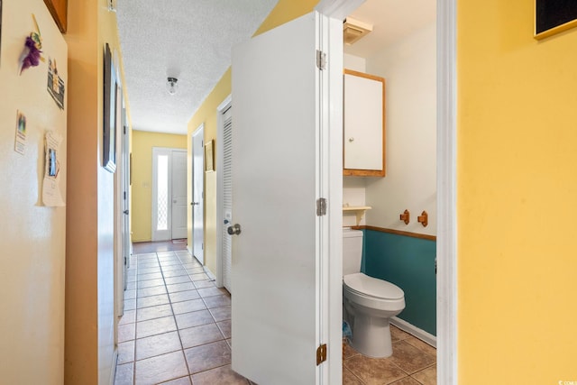 hallway featuring tile patterned flooring and a textured ceiling