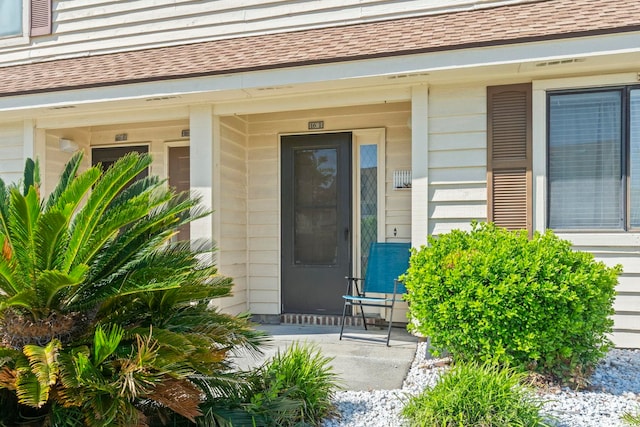 property entrance with covered porch and a shingled roof