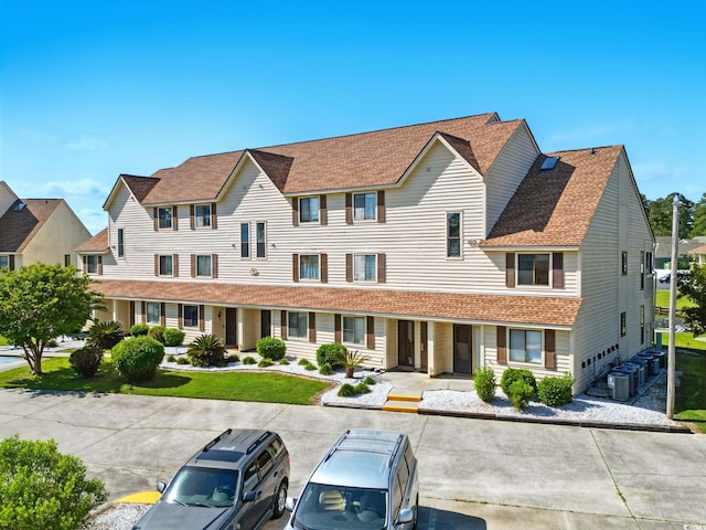 view of front of house featuring cooling unit, a residential view, uncovered parking, and roof with shingles