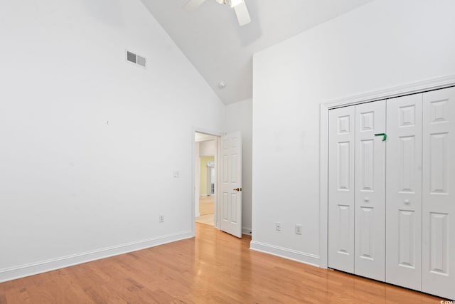 unfurnished bedroom featuring light wood-type flooring, baseboards, visible vents, a closet, and high vaulted ceiling