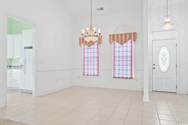 foyer with an inviting chandelier, vaulted ceiling, visible vents, light tile patterned flooring, and baseboards