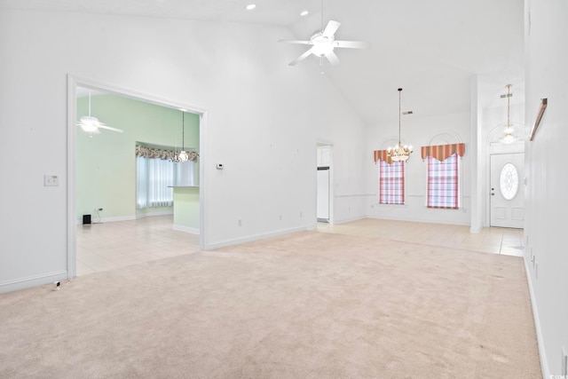 unfurnished living room featuring ceiling fan with notable chandelier, carpet flooring, high vaulted ceiling, and tile patterned flooring