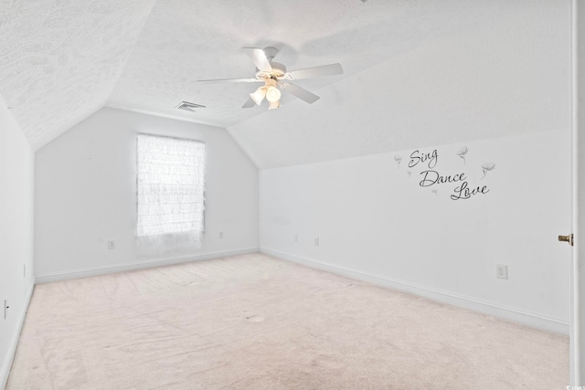 additional living space featuring a textured ceiling, lofted ceiling, visible vents, and baseboards