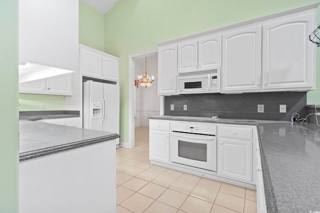 kitchen featuring an inviting chandelier, backsplash, light tile patterned floors, white appliances, and white cabinetry