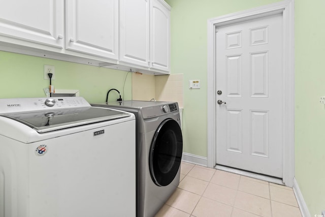 washroom featuring light tile patterned floors, washing machine and clothes dryer, cabinet space, and baseboards