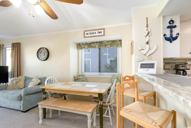 carpeted dining space with a ceiling fan, crown molding, and a textured ceiling