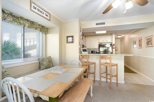 dining room featuring a textured ceiling, visible vents, light colored carpet, ceiling fan, and crown molding