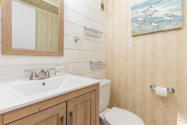 bathroom with wallpapered walls, visible vents, toilet, and vanity