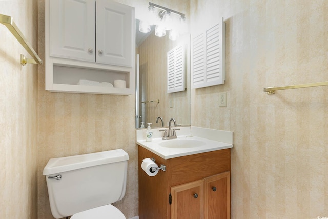 bathroom with wallpapered walls, vanity, and toilet