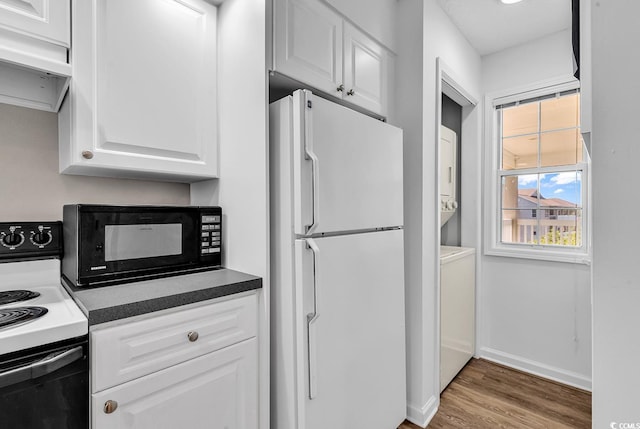 4430 Eastport Blvd Unit L15, Little River, SC 29566 - kitchen featuring freestanding refrigerator, black microwave, range with electric stovetop, stacked washer / dryer, and white cabinetry