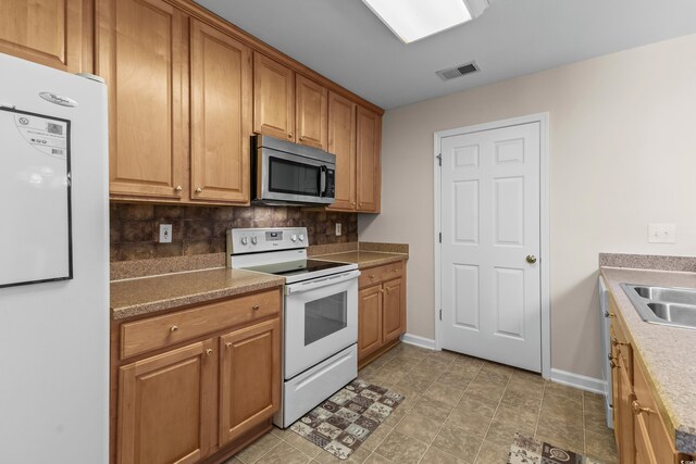1004 Harvester Cir Unit 1004, Myrtle Beach, SC 29579 - kitchen with white appliances, decorative backsplash, baseboards, a sink, and brown cabinets