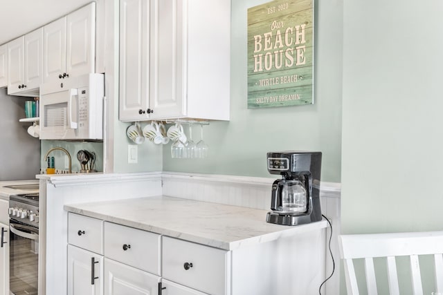 bar featuring stainless steel range, wainscoting, and white microwave