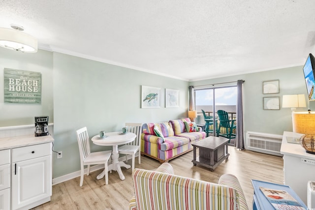living room with crown molding, baseboards, light wood-style flooring, and a textured ceiling