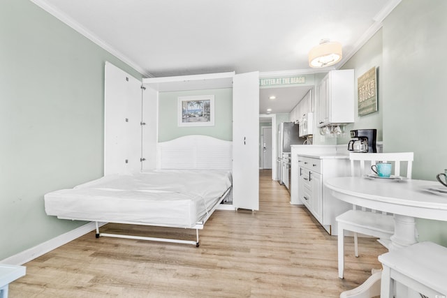 bedroom featuring crown molding, baseboards, light wood-style floors, and freestanding refrigerator