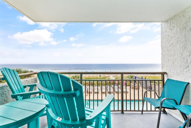 balcony with a water view and a view of the beach