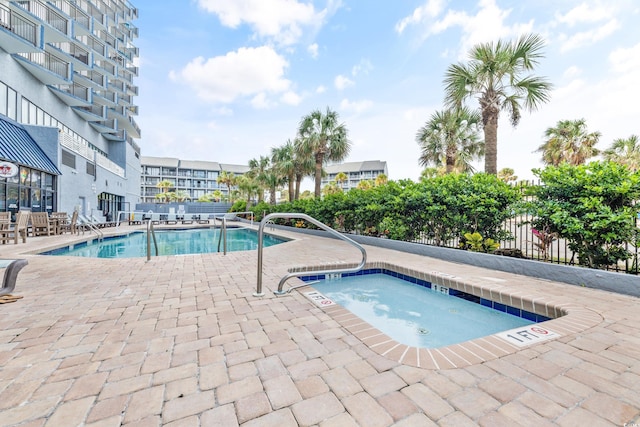 community pool with a patio, a community hot tub, and fence