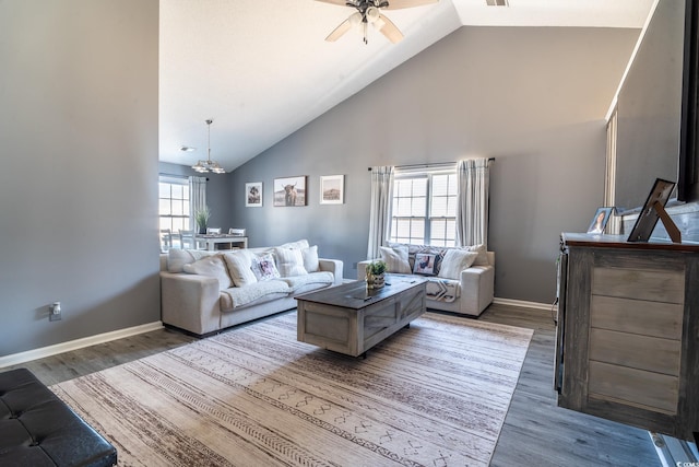 living area featuring a chandelier, wood finished floors, ceiling fan, baseboards, and high vaulted ceiling