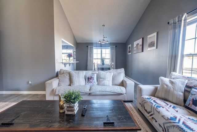 living room featuring vaulted ceiling, a chandelier, wood finished floors, and baseboards