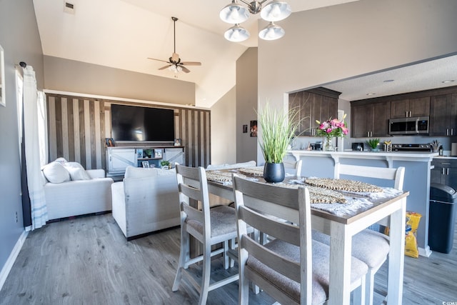 dining area with ceiling fan, high vaulted ceiling, light wood-type flooring, and baseboards