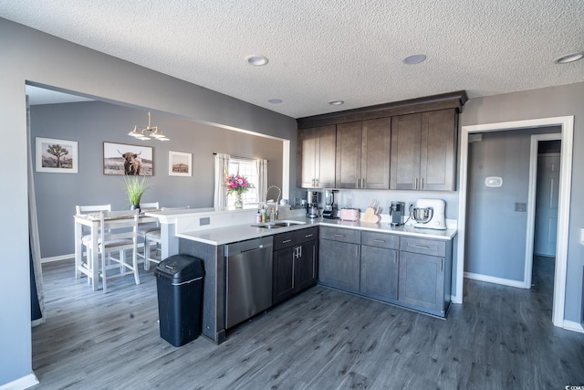 kitchen featuring dishwasher, a peninsula, light countertops, a chandelier, and dark wood-style floors