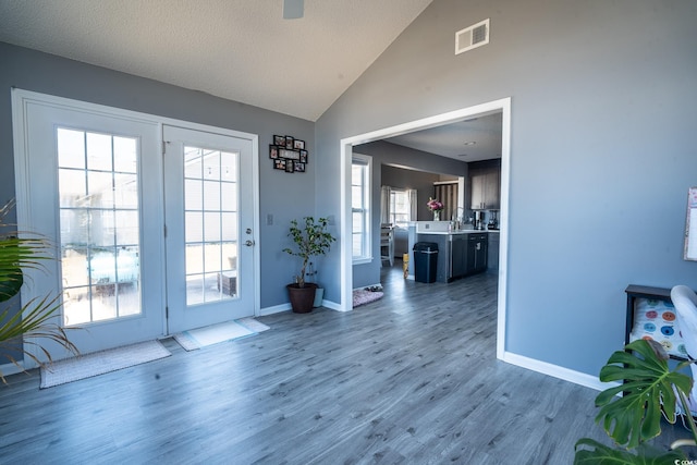 doorway featuring wood finished floors, baseboards, and high vaulted ceiling