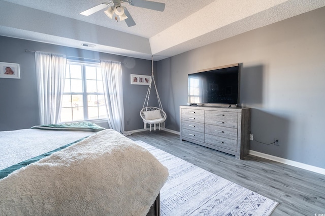 bedroom featuring baseboards, wood finished floors, a textured ceiling, and ceiling fan