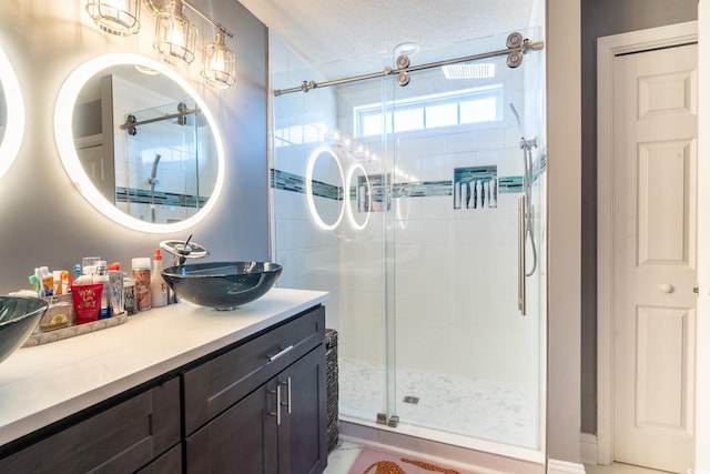 full bathroom with a stall shower, vanity, and a textured ceiling