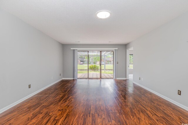 spare room with baseboards and dark wood-style flooring