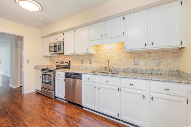 kitchen with tasteful backsplash, stainless steel appliances, white cabinets, a sink, and dark wood-style floors
