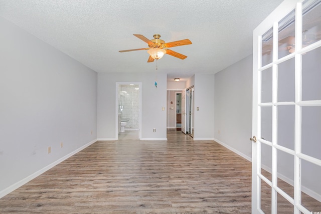 empty room with wood finished floors, ceiling fan, a textured ceiling, and french doors