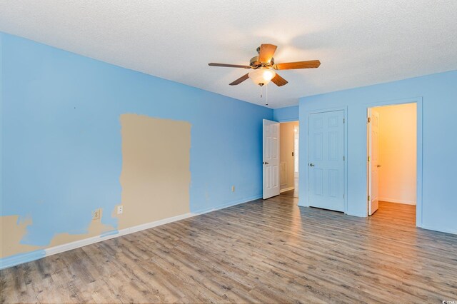 unfurnished bedroom featuring a textured ceiling, wood finished floors, ceiling fan, and baseboards