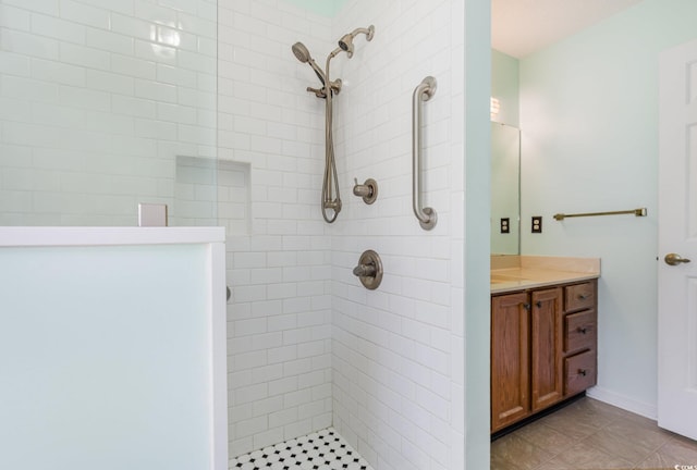 full bath featuring tile patterned flooring, tiled shower, and vanity