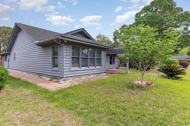 view of side of home featuring a lawn and a shingled roof