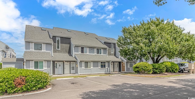 view of front of home featuring uncovered parking, a shingled roof, and a residential view