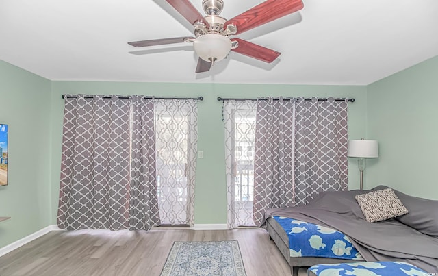bedroom featuring wood finished floors, baseboards, and a ceiling fan