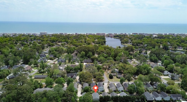 aerial overview of property's location with a large body of water, a tree filled landscape, and nearby suburban area