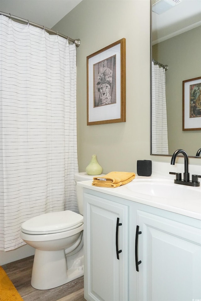 bathroom with toilet, wood finished floors, and vanity