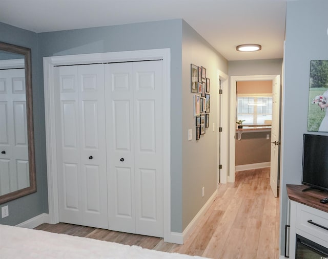 hall featuring light wood finished floors and baseboards
